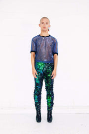 Man wearing green sequin pants and blue mesh t-shirt as party wear