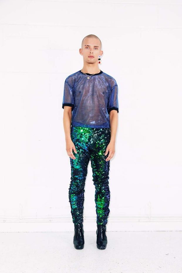 Man wearing green sequin pants and blue mesh t-shirt as party wear