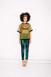 Woman wearing green sequin pants and gold sheer t-shirt at festival