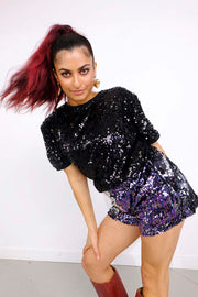 woman wearing black sequin t-shirt and purple blue sequin shorts as part of a festival outfit for women 