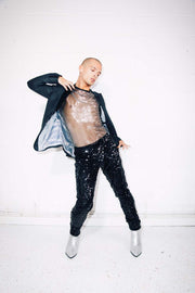 Man wearing black sequin pants and silver sheer tshirt as sequin suit