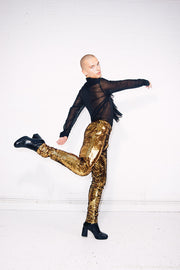 Man wearing gold sequin pants dancing in a festival outfit for men