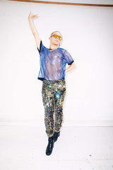 Man wearing rainbow sequin leggings and sheer blue top for festival outfit for pride outfit