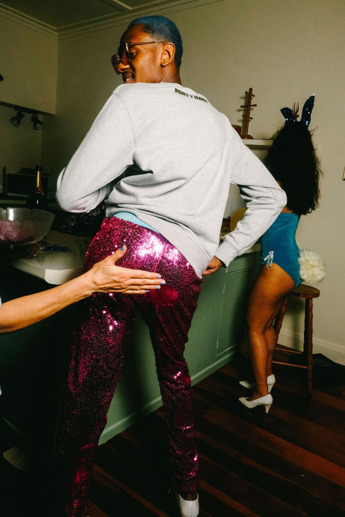 https://sparklebutt.co.uk/cdn/shop/files/Man-with-blue-hair-at-party-wearing-pink-sequin-pants-and-grey-jumper-getting-his-butt-slapped_1024x1024.jpg?v=1694499266