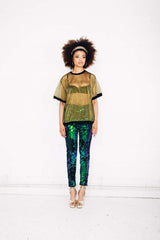 Woman wearing green sequin pants and gold sheer t-shirt at festival