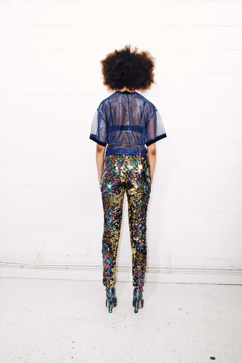 Woman wearing rainbow sequin pants and sheer blue t-shirt for pride event