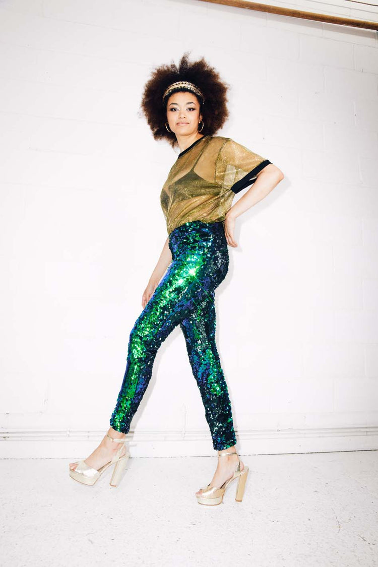 Woman wearing green sequin pants and gold sheer t-shirt at festival