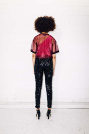 Woman wearing black sequin pants and red mesh t-shirt as party outfit